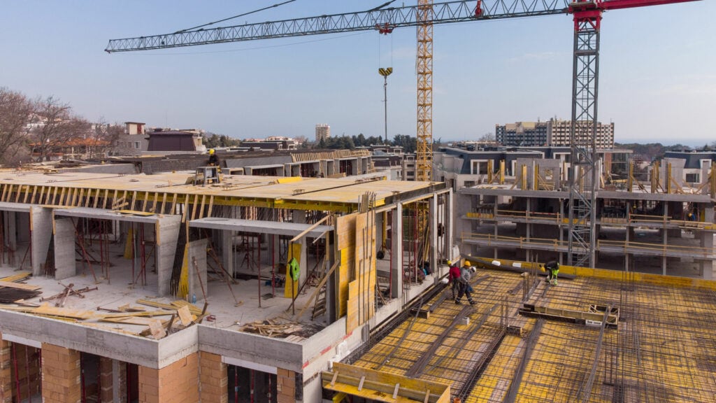 Construction site with cranes and workers building multi-story structures, showcasing advanced construction techniques and infrastructure development.