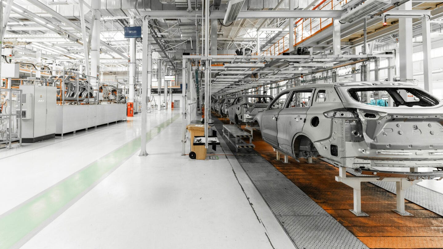 High-tech automotive manufacturing factory with robotic assembly lines and car body frames.