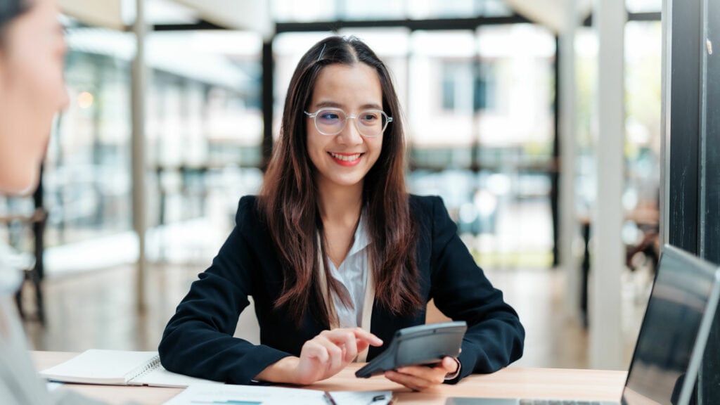 Smiling woman using a smartphone in a modern office or co-working space.