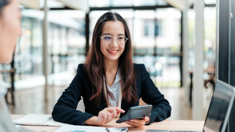Smiling woman using a smartphone in a modern office or co-working space.