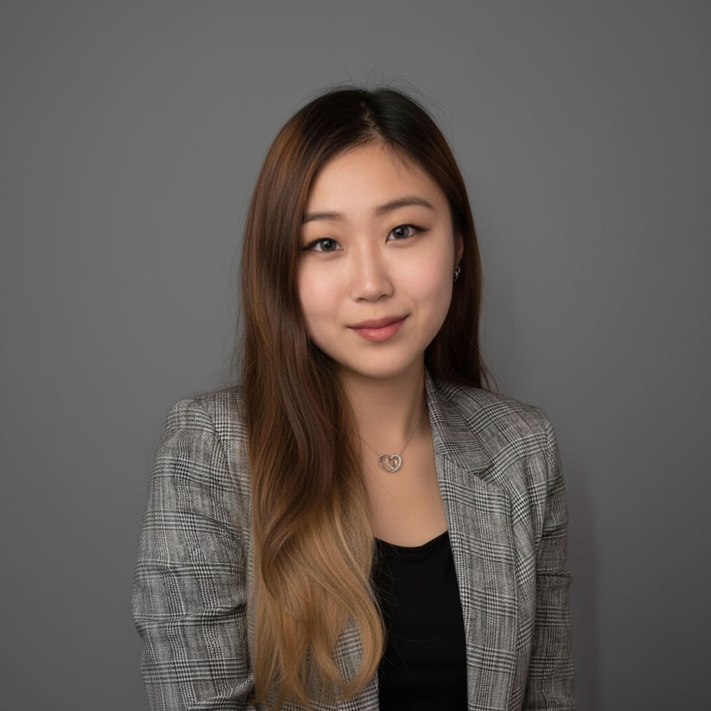 Asian woman in professional attire with long hair, smiling against gray background.