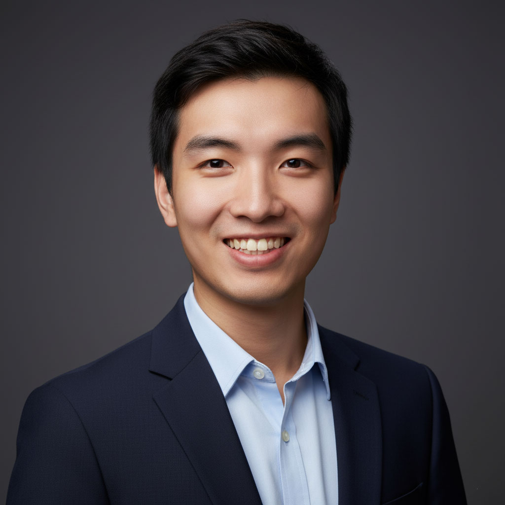 Professional business portrait of a young Asian man in formal suit, smiling, gray background.