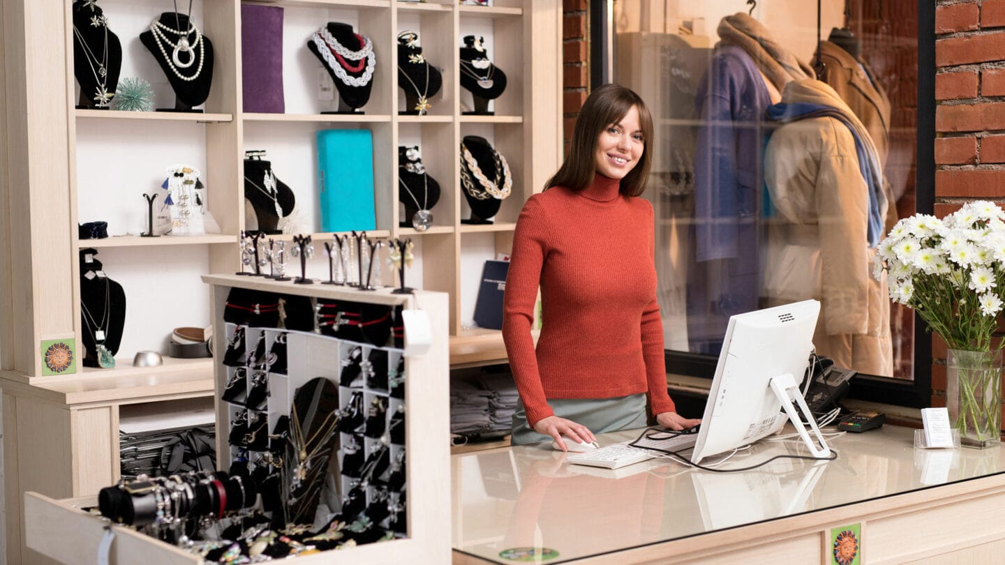 Colorful jewelry display at a retail store with a cheerful staff member.