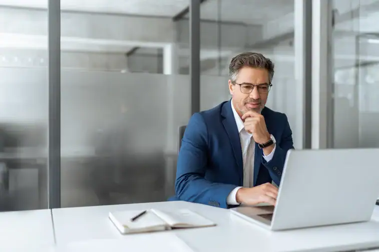 Professional businessman working on a laptop in modern office setting.
