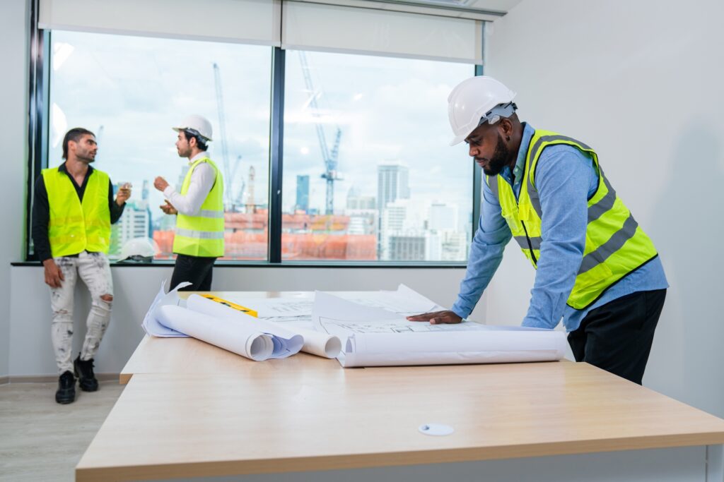 High-rise construction team reviewing blueprints at modern office site.