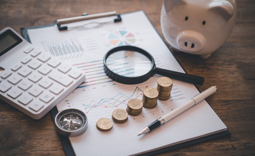 Affordable financial planning and investment analysis with coins, calculator, magnifying glass, piggy bank, and charts.