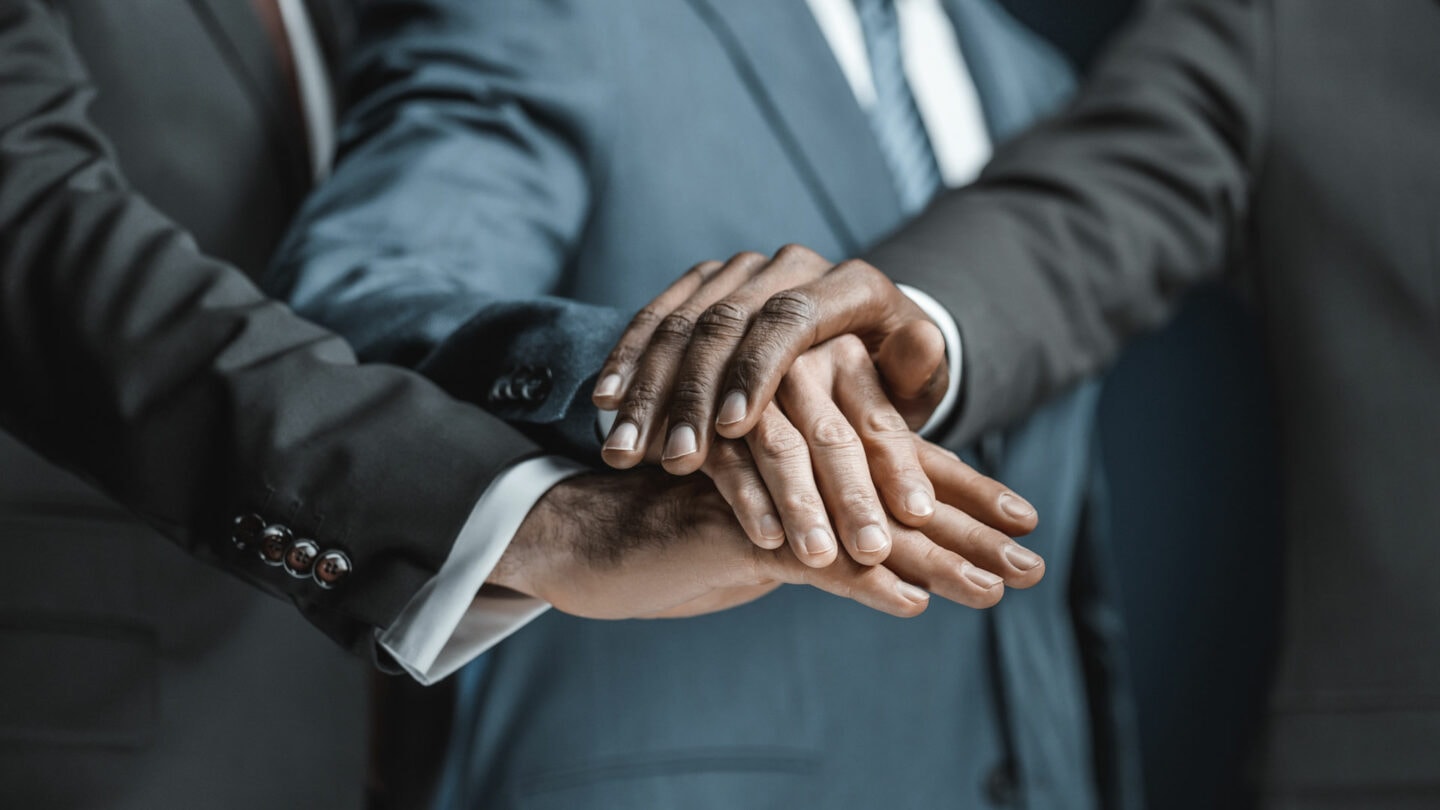 Diverse business professionals shaking hands, symbolizing partnership and collaboration.
