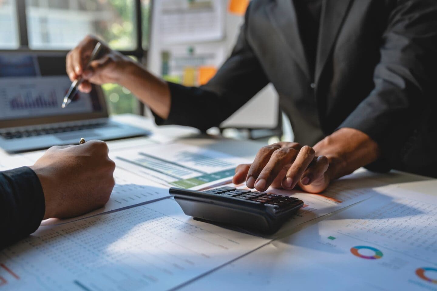 1. Business professionals analyzing financial data with laptops and calculators in an office environment.