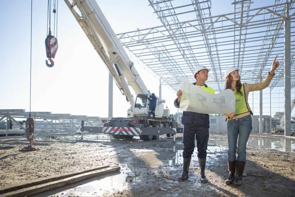 Construction site with engineers inspecting blueprints and a crane for structural development.
