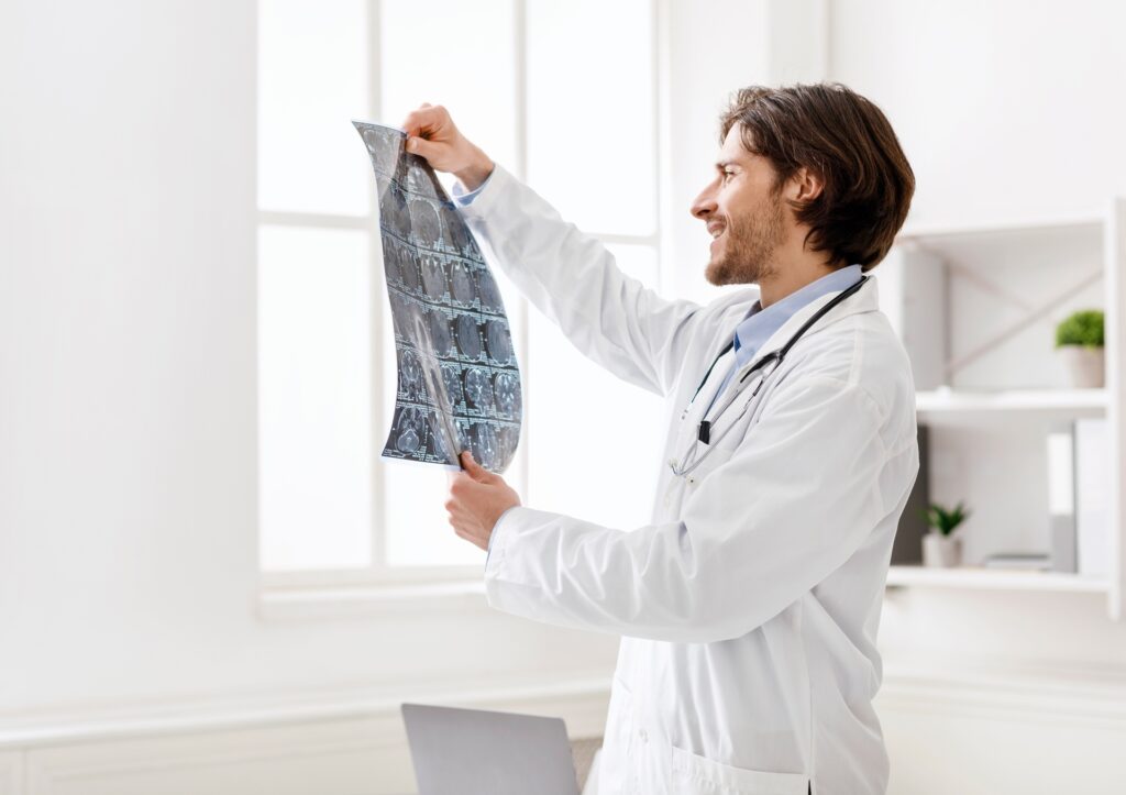 Bright-eyed doctor analyzing brain MRI scans in a modern medical office.