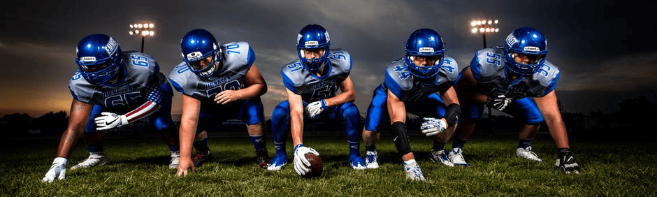 Football players in action on a dark field, emphasizing team strategy and athletic performance.