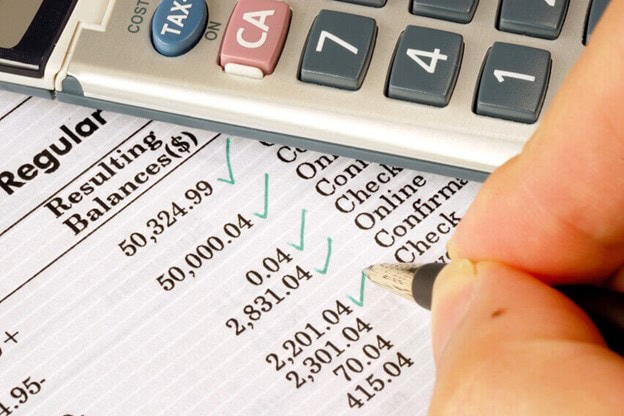 Detailed financial statement with calculator; accounting, bookkeeping, or tax preparation concept.