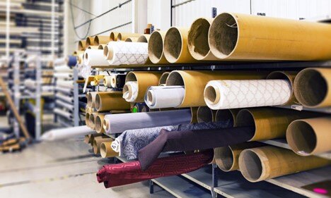 Industrial fabric and textile rolls on storage racks at Concentrus supplier warehouse.