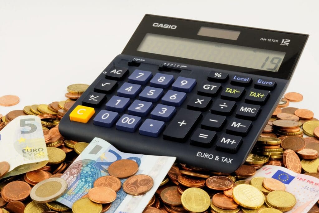 Calculator with coins and euro banknotes, financial planning and cash management concept.