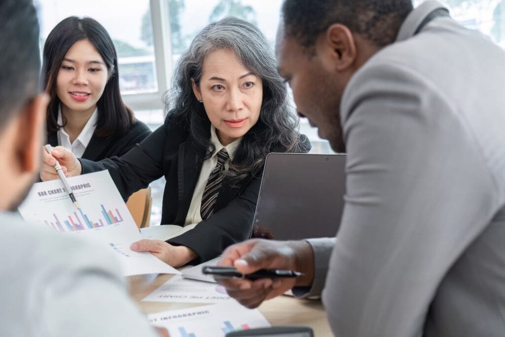Diverse professionals discussing data and charts in a modern office meeting.