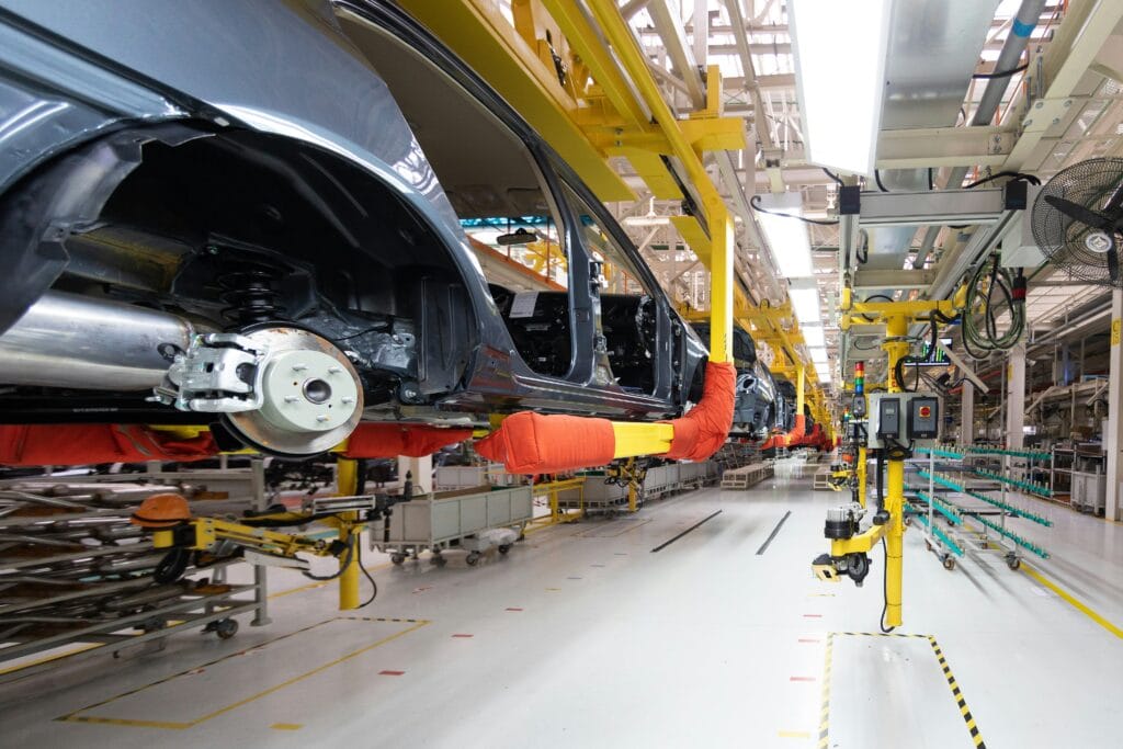 Automotive manufacturing assembly line with black car frames in a high-tech factory setting.