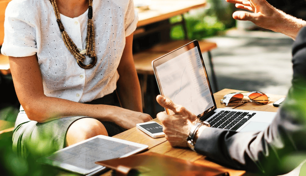 High-level business meeting outdoors with laptops and tablets, Focus on digital collaboration and technology integration.