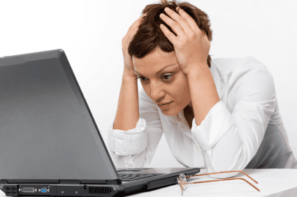 Overwhelmed woman working on a laptop, stressed and anxious, representing workplace stress and mental health.