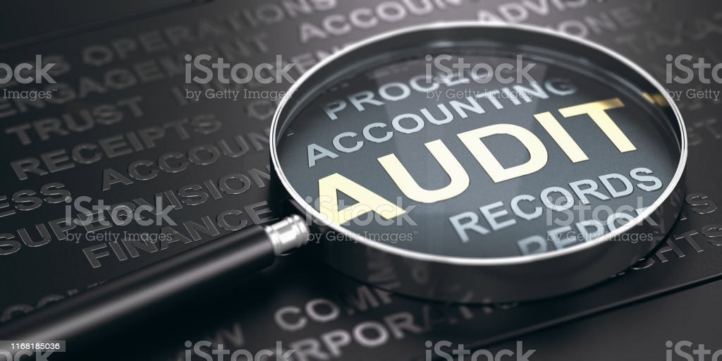 Audit inspection with magnifying glass over financial documents and records.