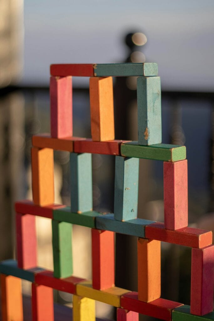 Colorful wooden block tower on outdoor deck with blurred background.