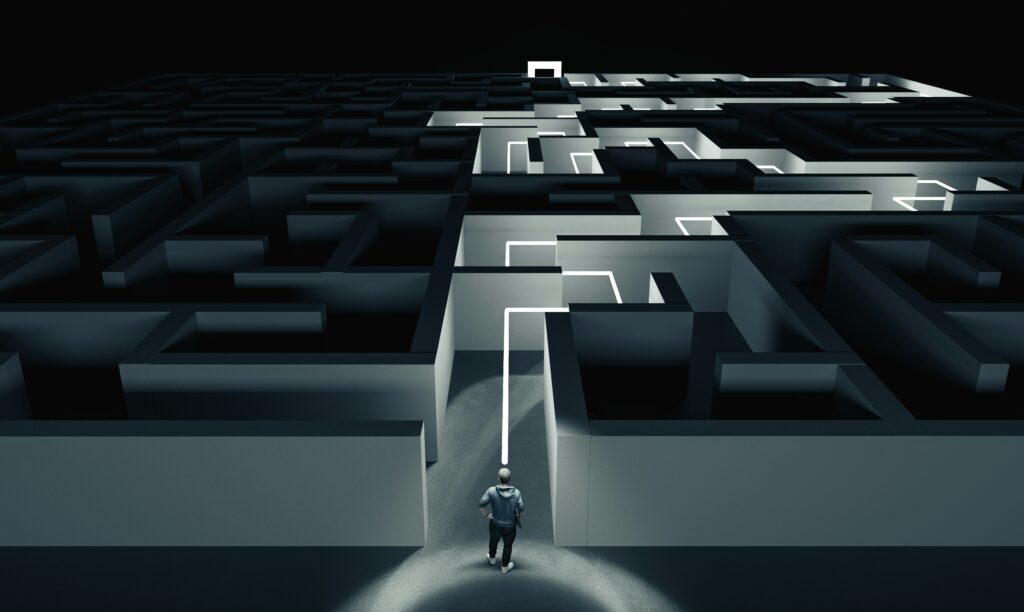 A person navigating a dark maze with illuminated pathways, symbolizing strategic problem-solving and guidance.
