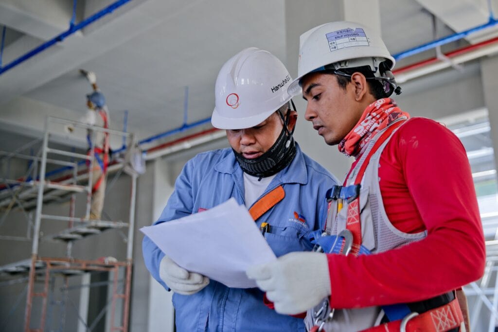 1. Safety workers reviewing construction plans on site at a high-rise building.