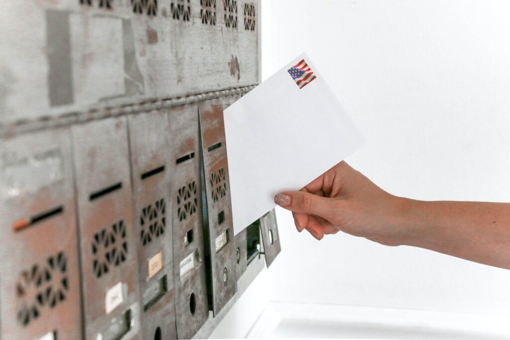 Mailbox with postage stamp and person inserting letter for direct marketing campaigns and customer engagement.