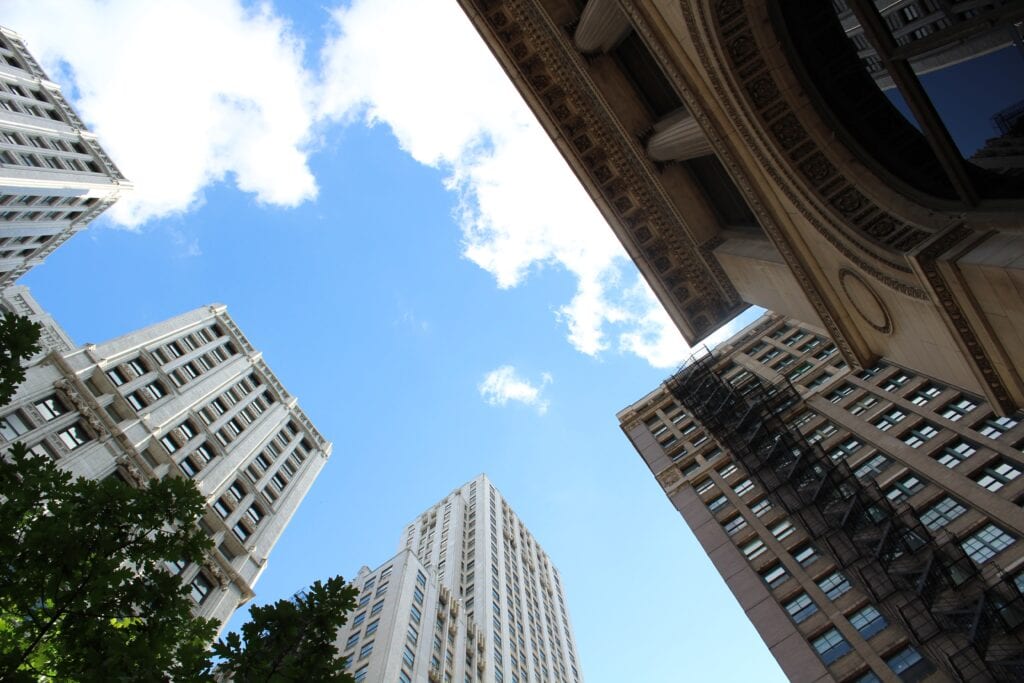 Vivid cityscape with historic and modern skyscrapers against a bright blue sky with white clouds.