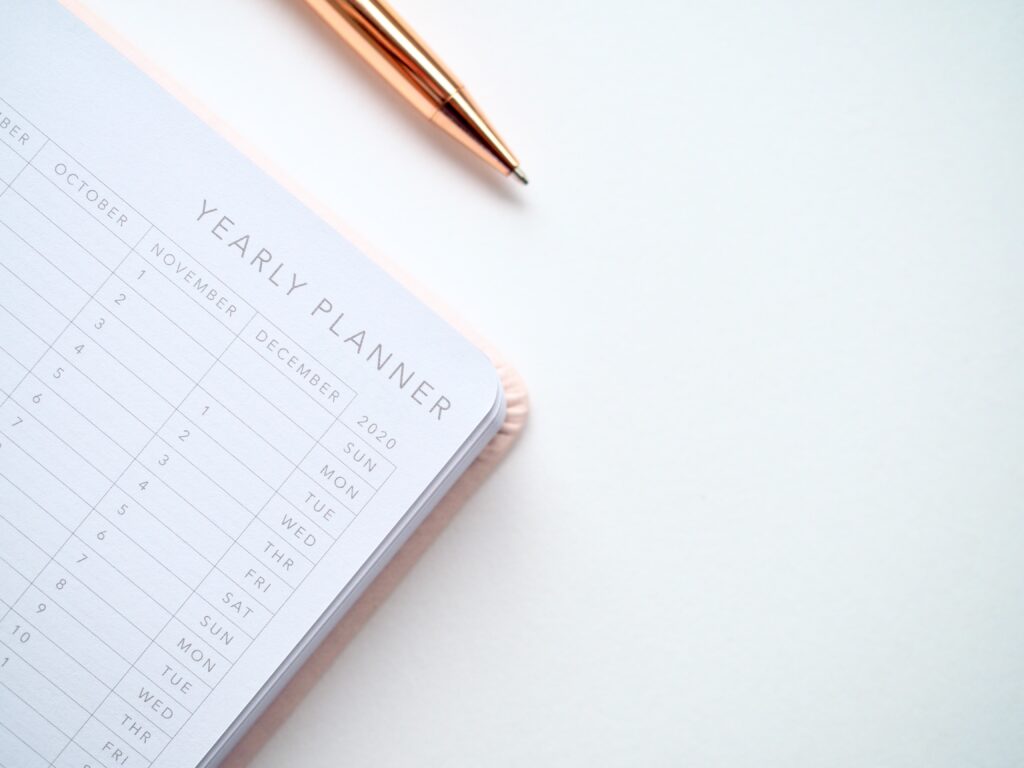 Organized yearly planner with spiral binding and rose gold pen on white background.