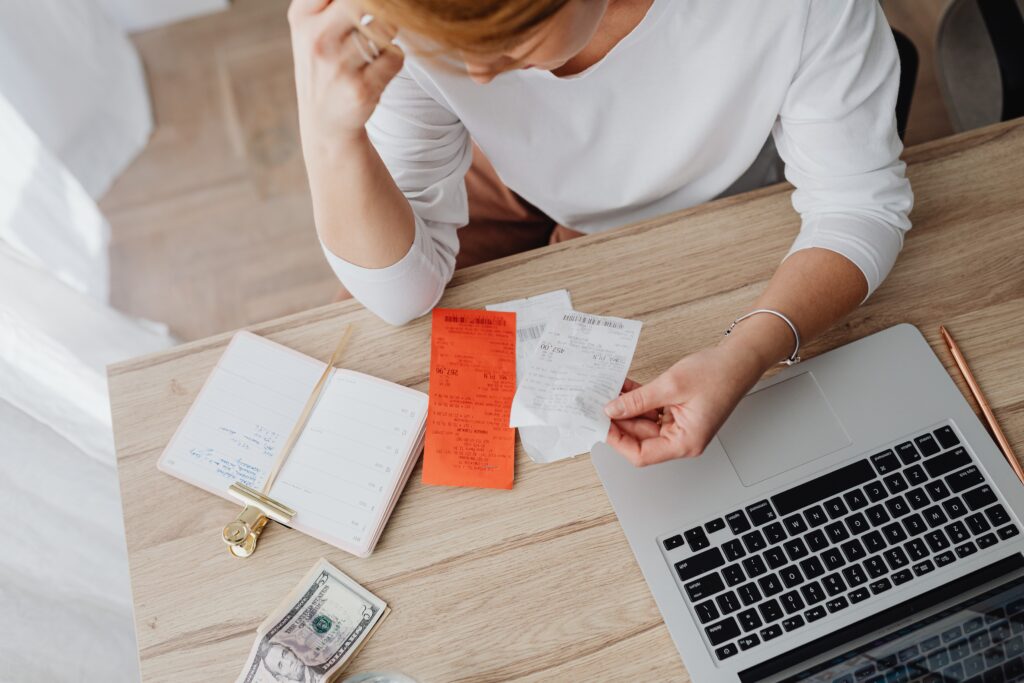 Unpaid bill receipt on wooden desk with laptop, planner, and cash, financial management concept.