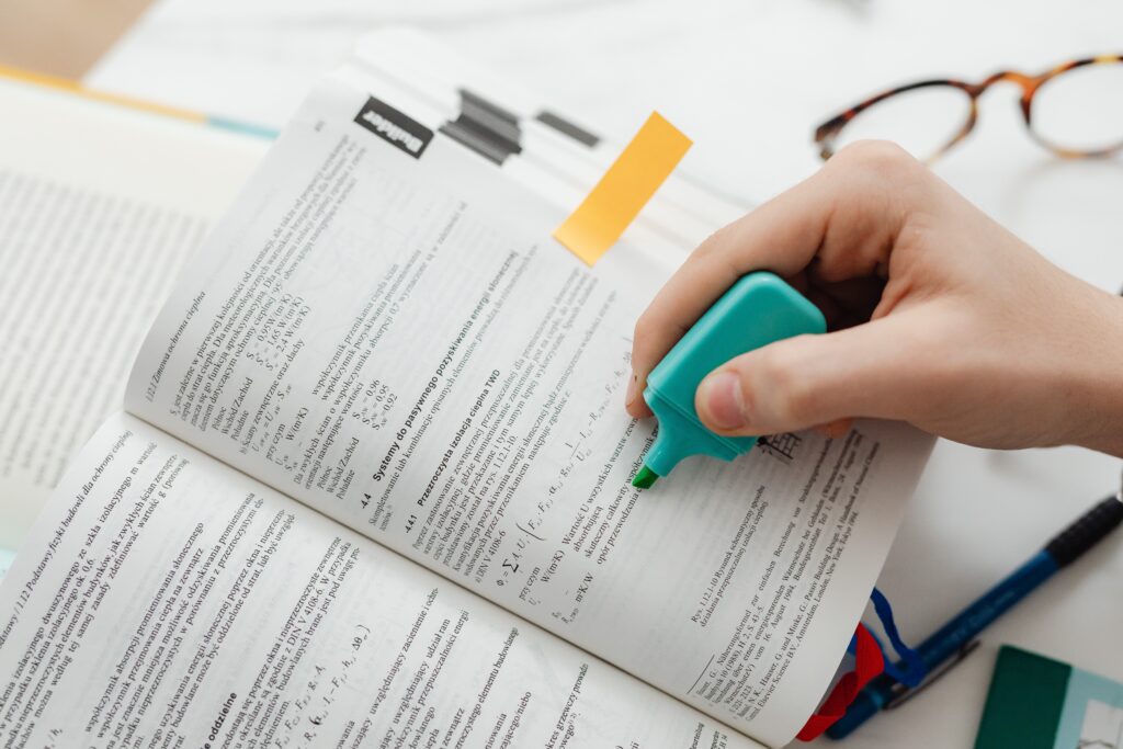 Highlighter marking textbook pages with scientific content and formulas.