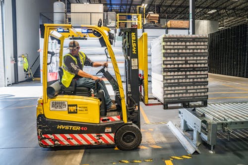 Forklift operating in a warehouse with stacked pallets for industrial logistics and supply chain efficiency.