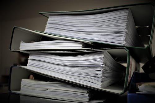 Extensive piles of paperwork and files in an office setting, representing document management.