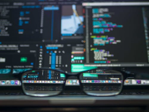 Code editing on computer screen with glasses, software development and programming concept.