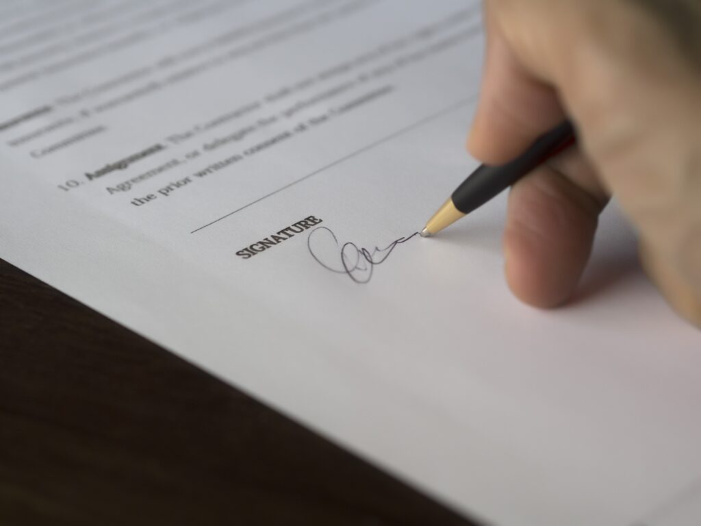 Signature being signed on a legal document or contract for official approval.