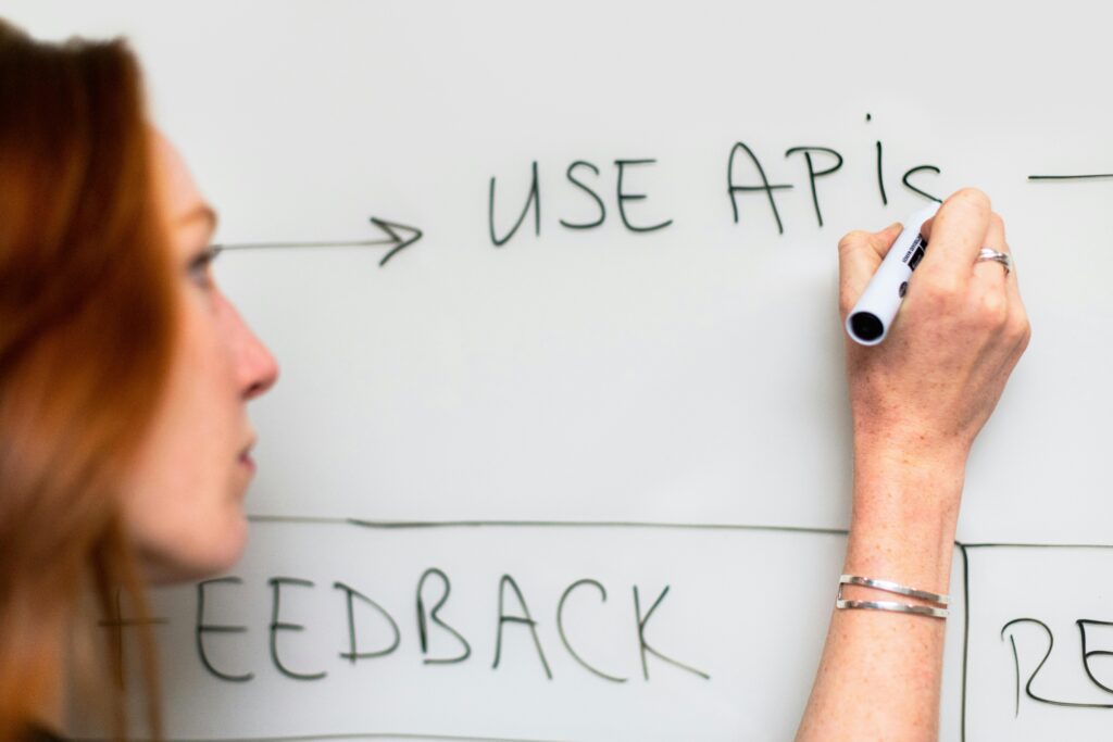 Elevated view of a person writing "USE API" on a whiteboard, tech, software development, coding, APIs, technology concepts.