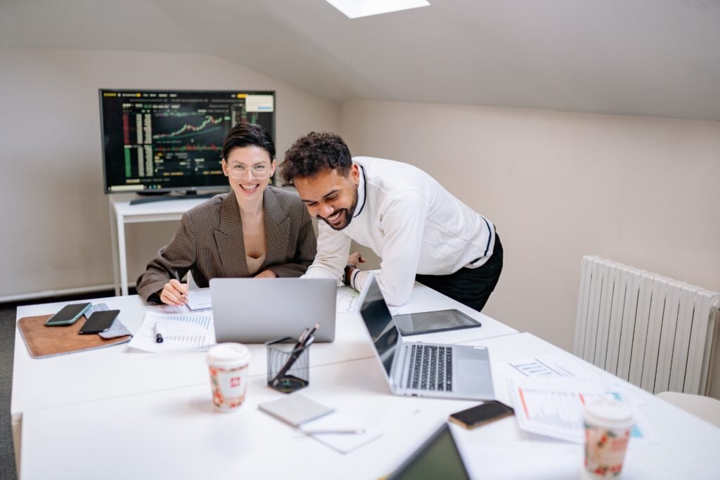 Analytics professionals reviewing financial data with computers and monitor showing stock charts.