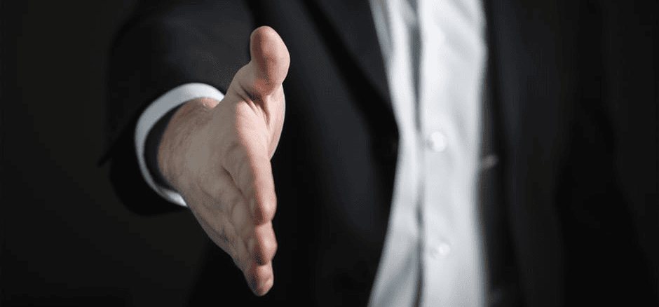 Extended hand offering handshake in business suit, representing trust and partnership.