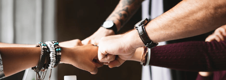 Diverse hands joining in a united fist bump for teamwork and collaboration.