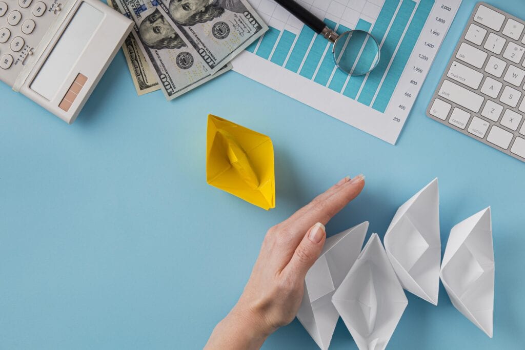 $ALT: Financial planning with paper boats, dollar bills, and analytics on blue background.