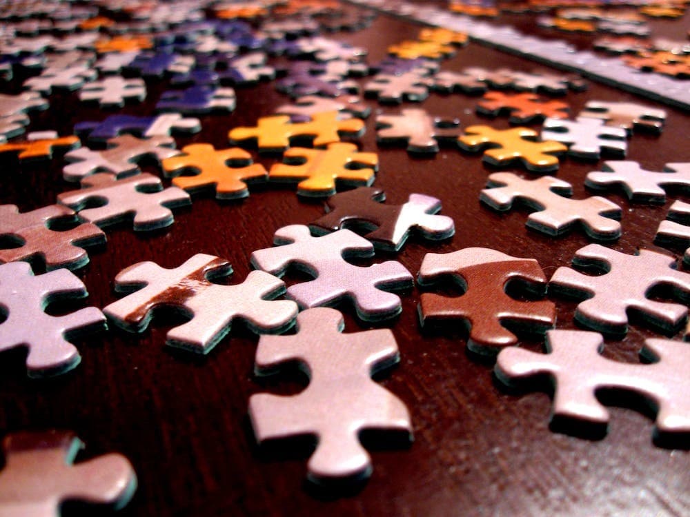 Colorful jigsaw puzzle pieces scattered on a wooden table.