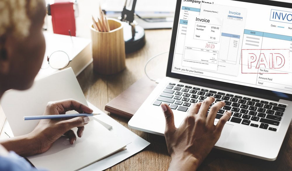 Invoice payment confirmation on laptop screen, financial document processing, business invoice management, accounting, digital finance.