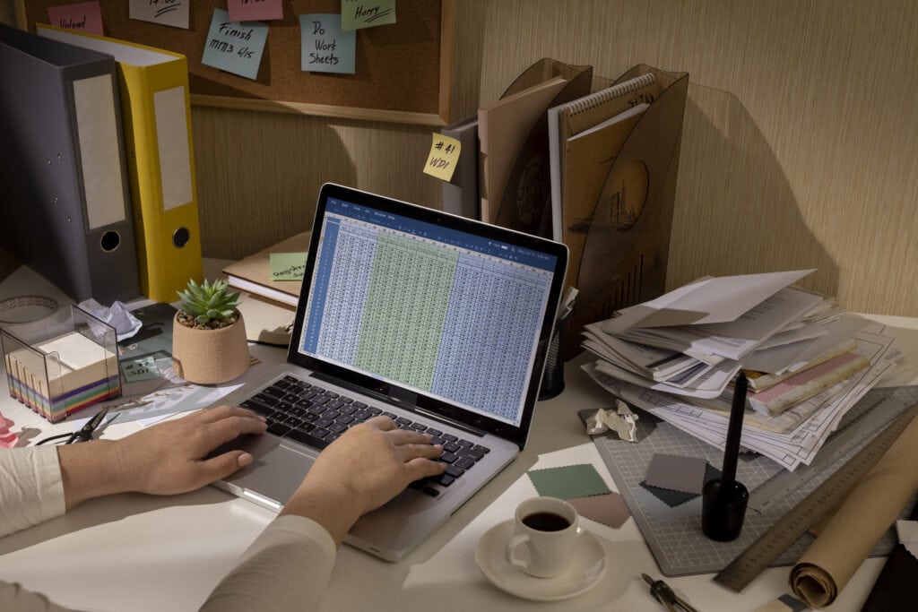 1. Computer screen displaying financial spreadsheets on cluttered office desk.