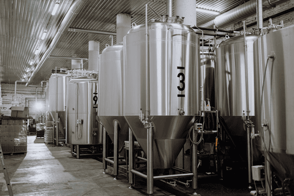 Stainless steel industrial tanks used for beverage or food processing in a manufacturing facility.