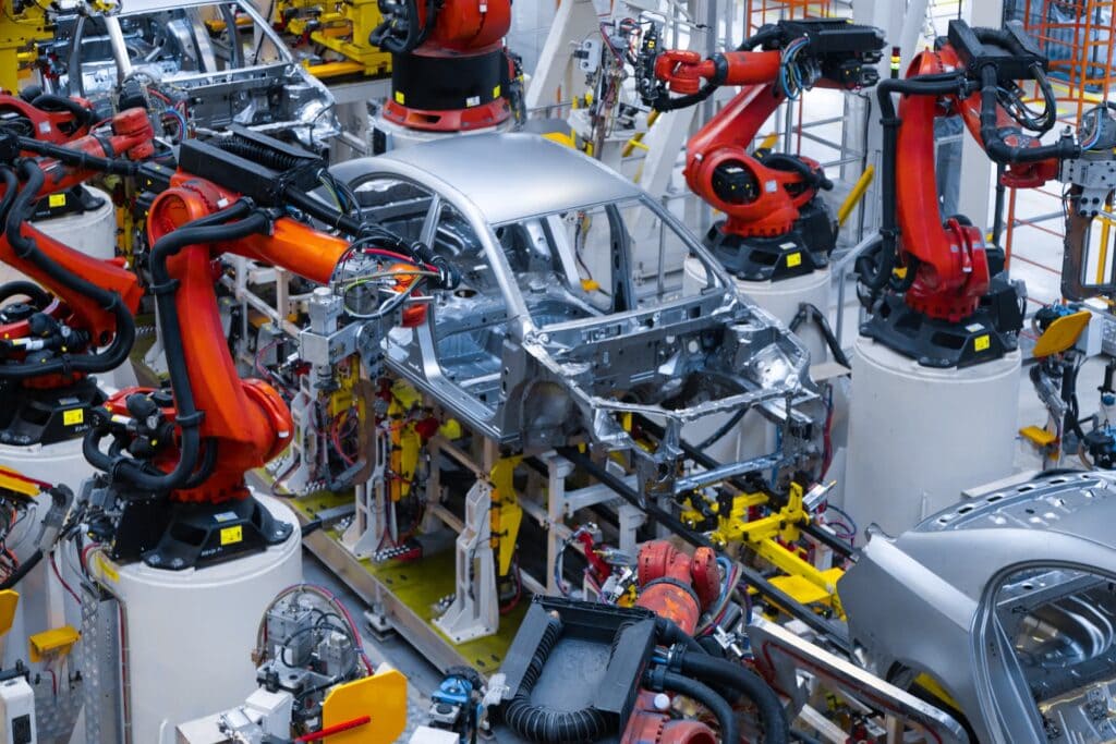 Robotics arms assembling car frame in automated manufacturing plant.