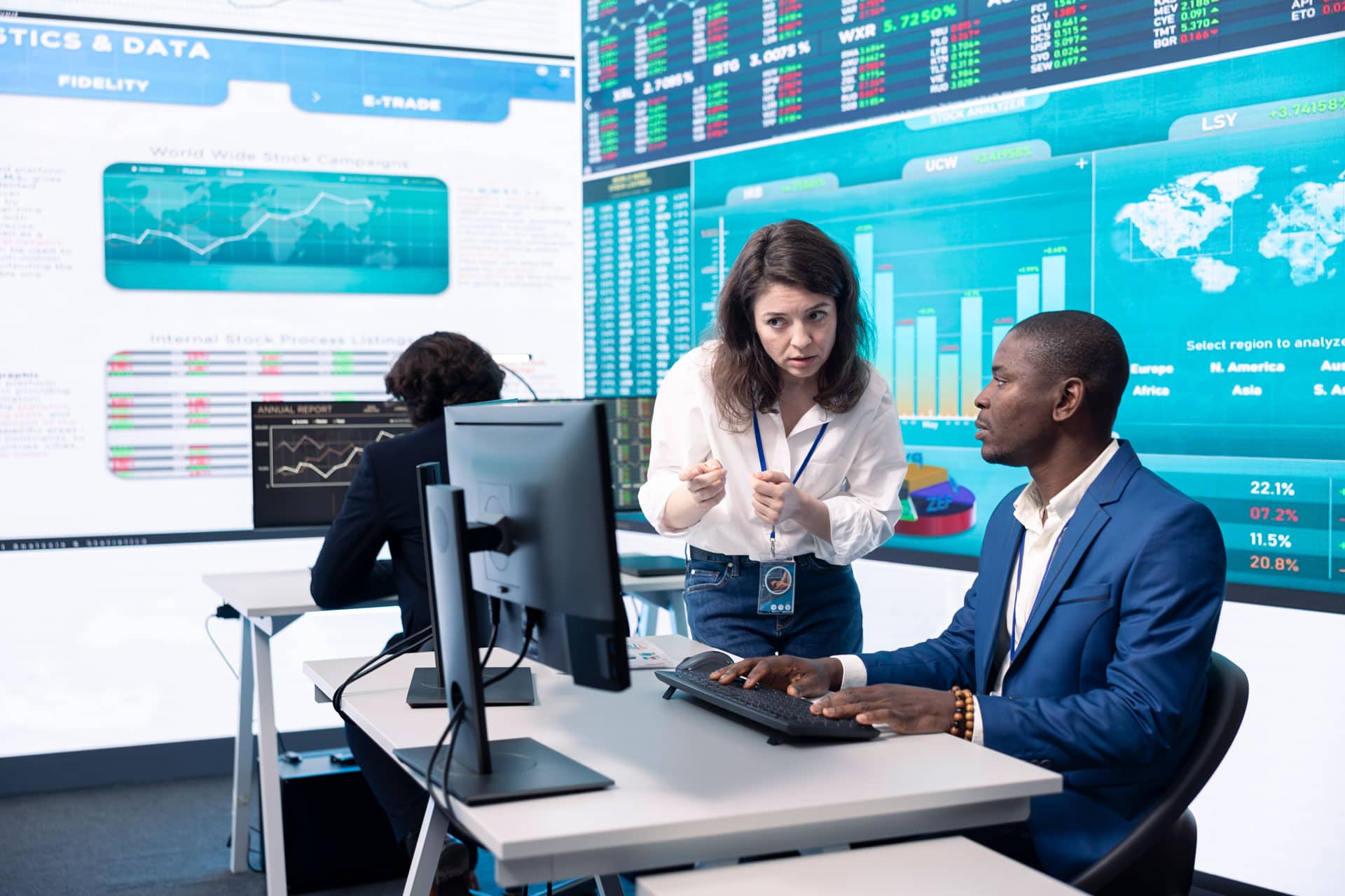 Advanced financial analysts monitoring stock market data on multiple digital screens at trading floor.