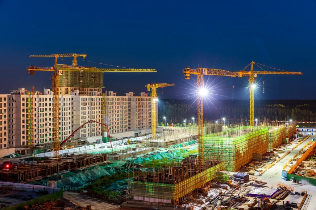Crane construction site at night, high-rise building, urban development, lighting, construction progress.