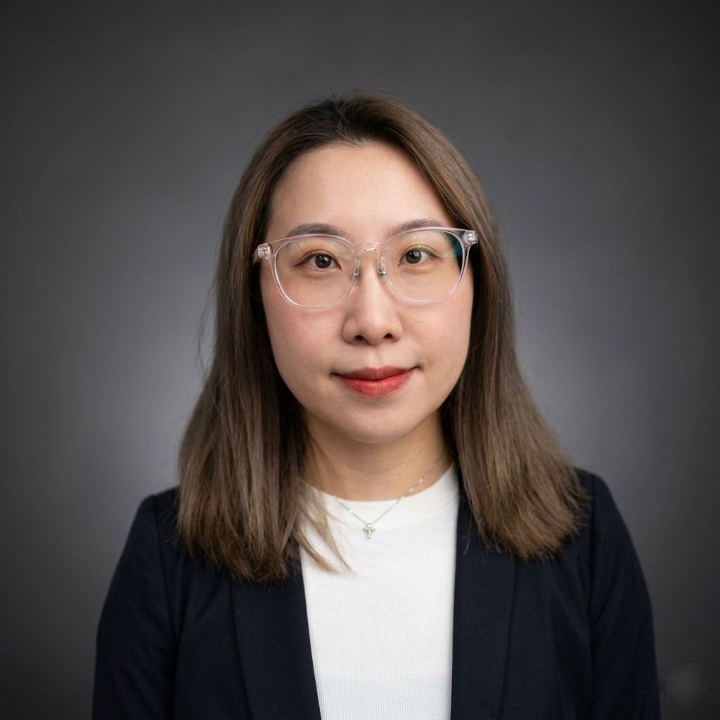 Professional woman wearing glasses, smiling, in a business setting.