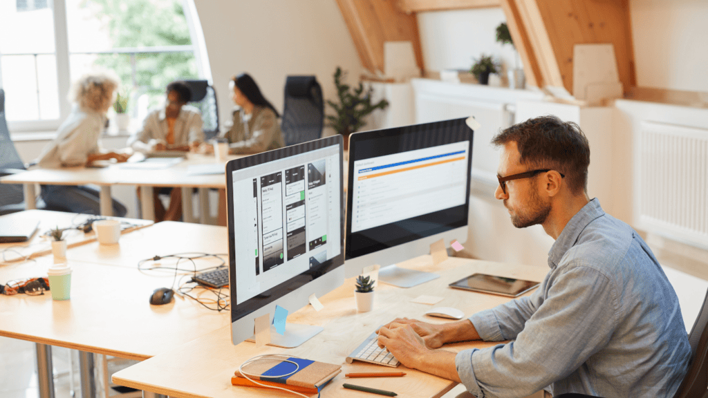 Business professional working on dual monitors with financial apps open.