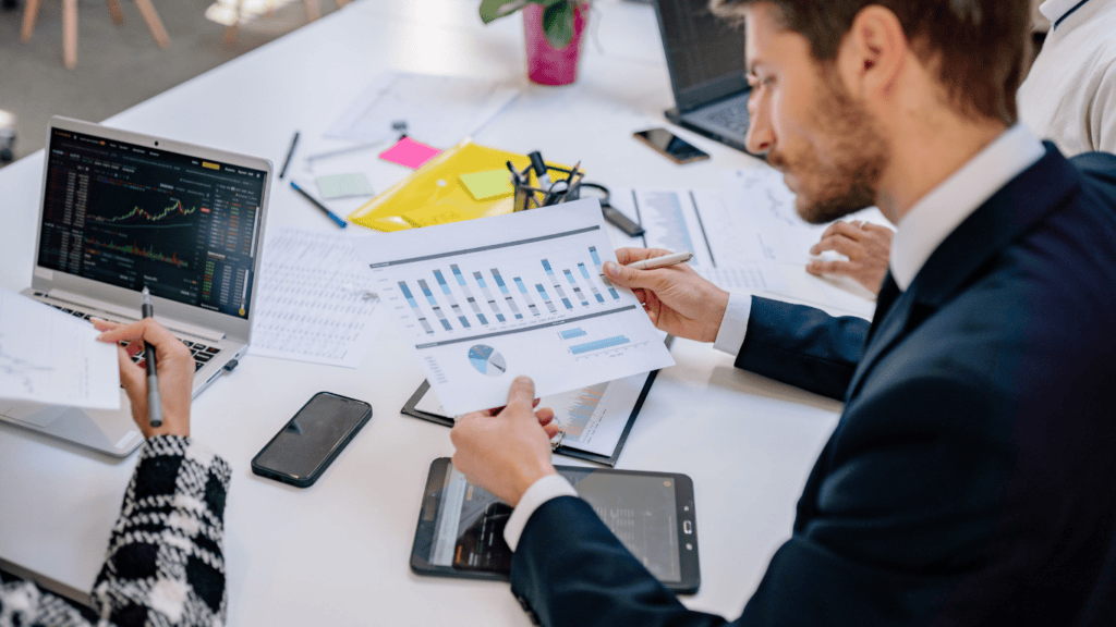 Business professionals analyzing financial data and charts on digital devices.